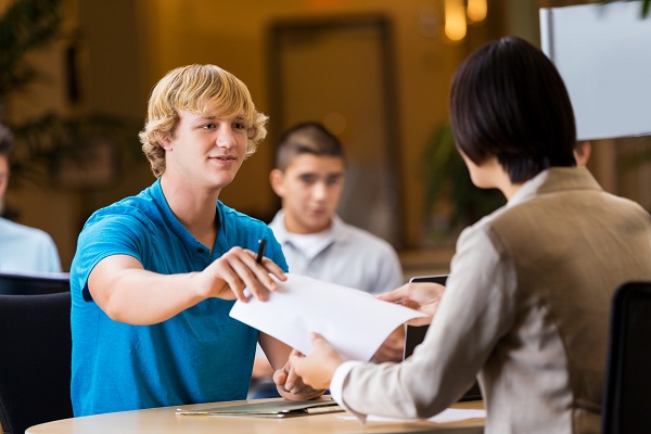 Young man handing resume to potential employer.